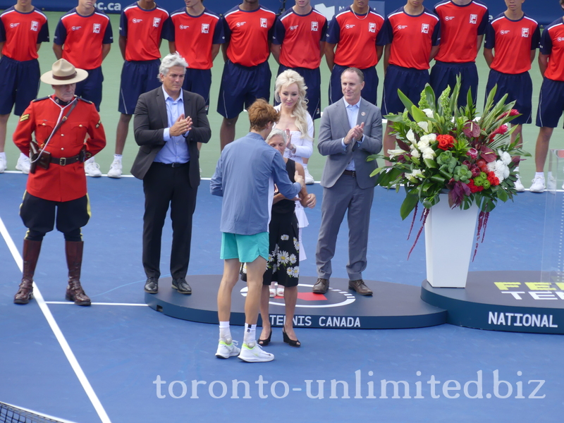 Jannik Sinner is accepting the Championship Trophy from Lucie Blanchet of the National Bank